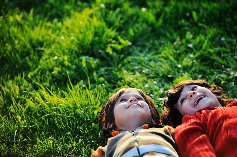 Happy kid enjoying sunny late summer and autumn day in nature on green grass